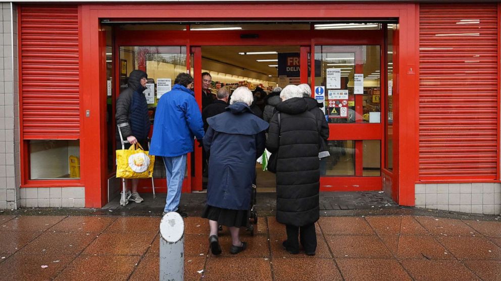 PHOTO: An elderly couple make their way into a supermarket in Liverpool, England, March 18, 2020, as some supermarkets offer a time specifically for elderly shoppers due to the novel coronavirus COVID-19 outbreak.