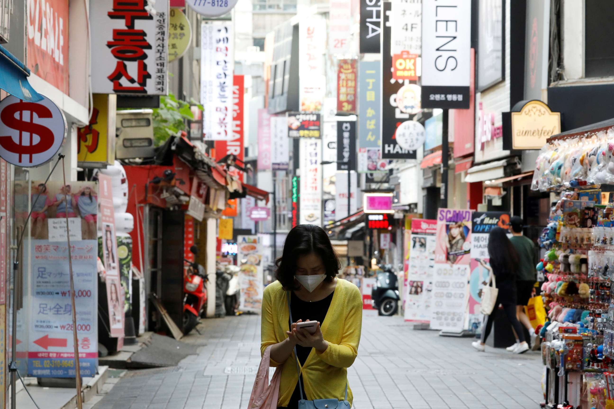 PHOTO: A woman wearing a mask looks at her mobile phone amid social distancing measures to avoid the spread of the coronavirus disease (COVID-19), in Myeongdong shopping district in Seoul, South Korea, May 28, 2020.