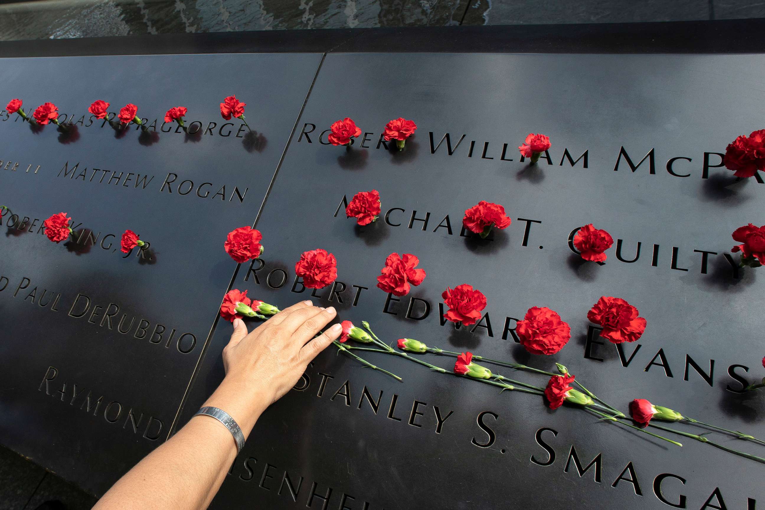 PHOTO: Norma Molina, of San Antonio, Texas, leaves flowers by the names of firefighters from Engine 33 at the September 11 Memorial, Sept. 9, 2019, in New York.