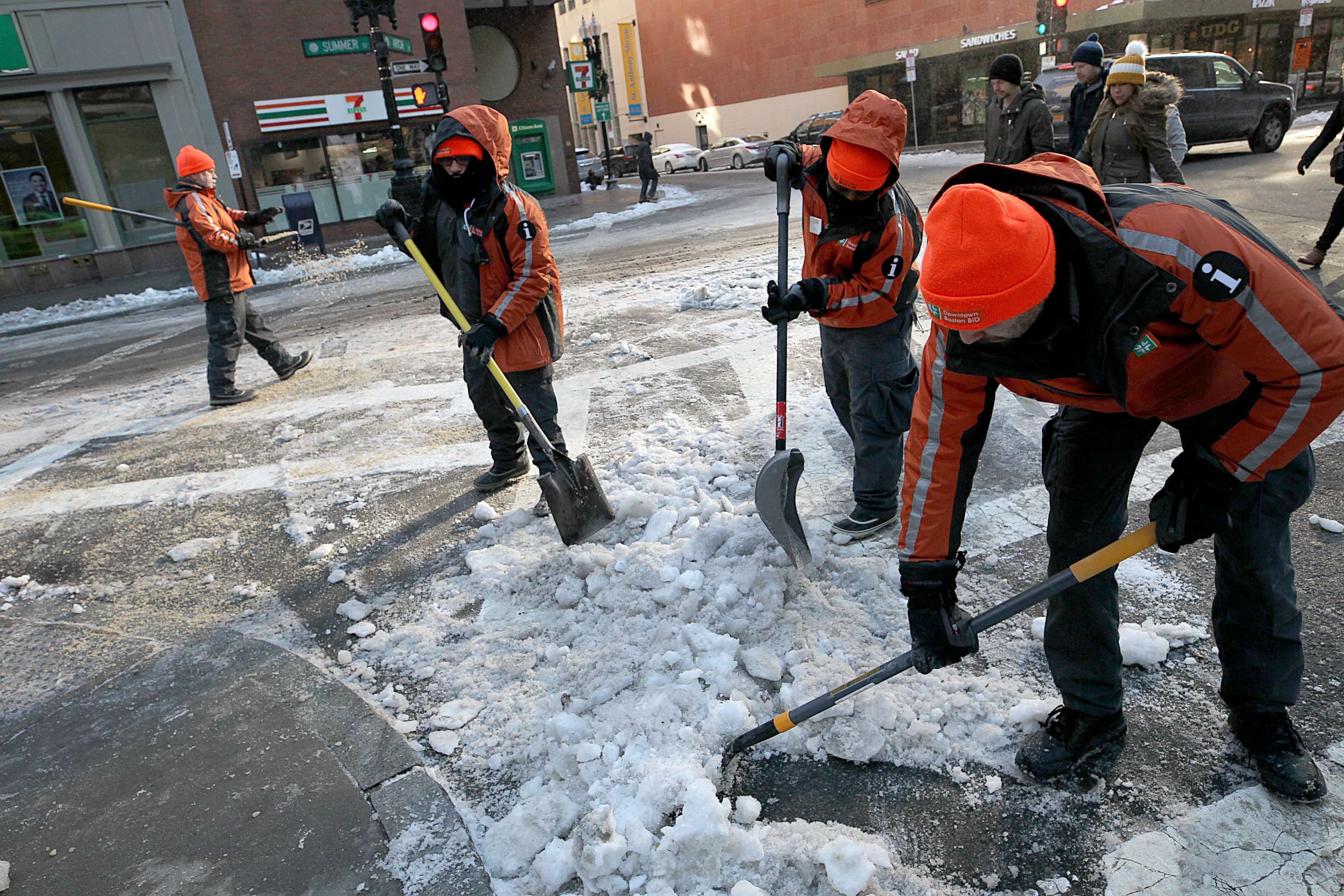 PHOTO: Workers shovel ice and snow from the intersection of Arch and Summer streets in downtown Boston, Dec. 26, 2017.