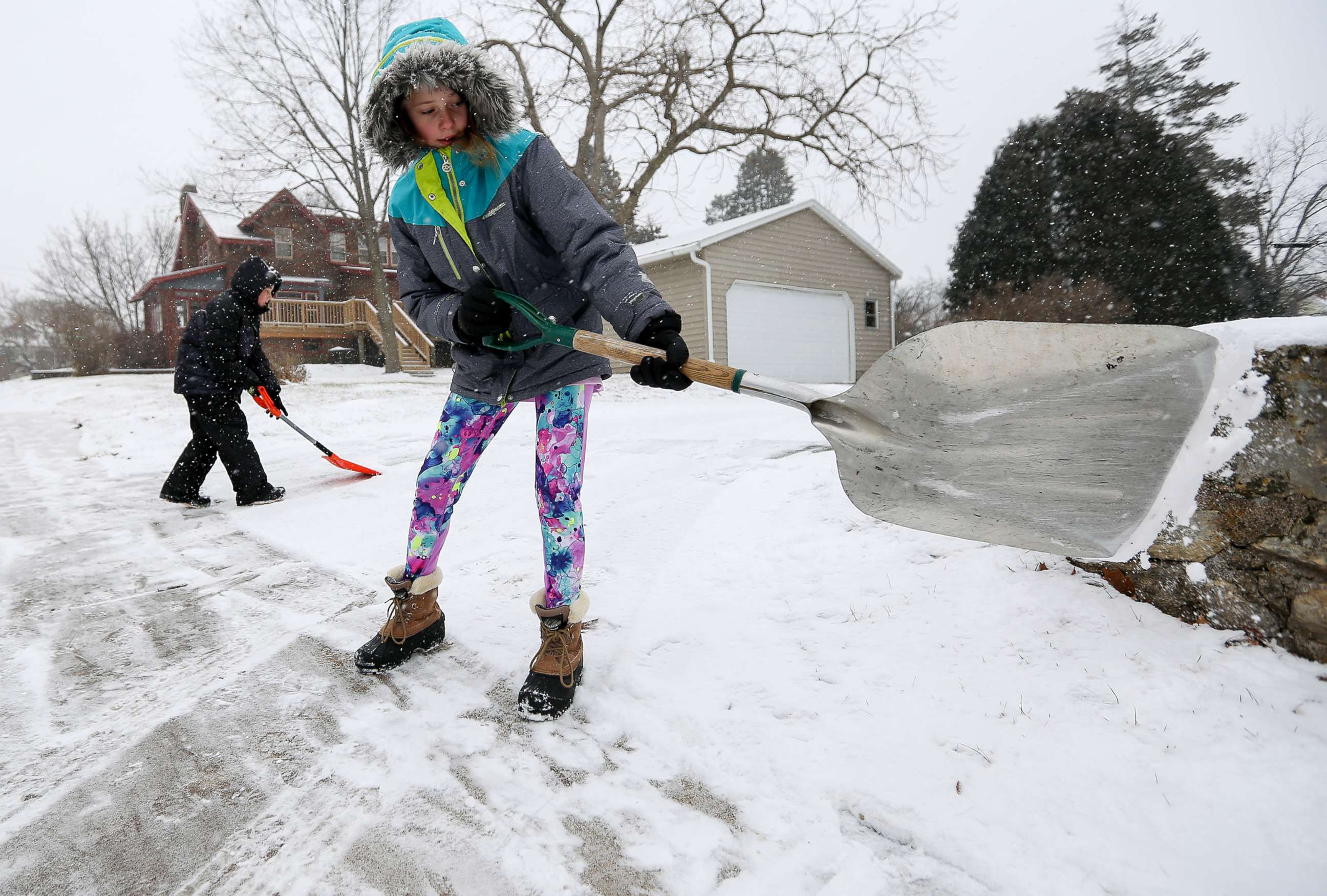 PHOTO: Karlee Winter, 11, and her brother Samuel Espinoza, 8, shovel snow from their neighbor's sidewalk in Dubuque, Iowa, Dec. 28, 2017. 