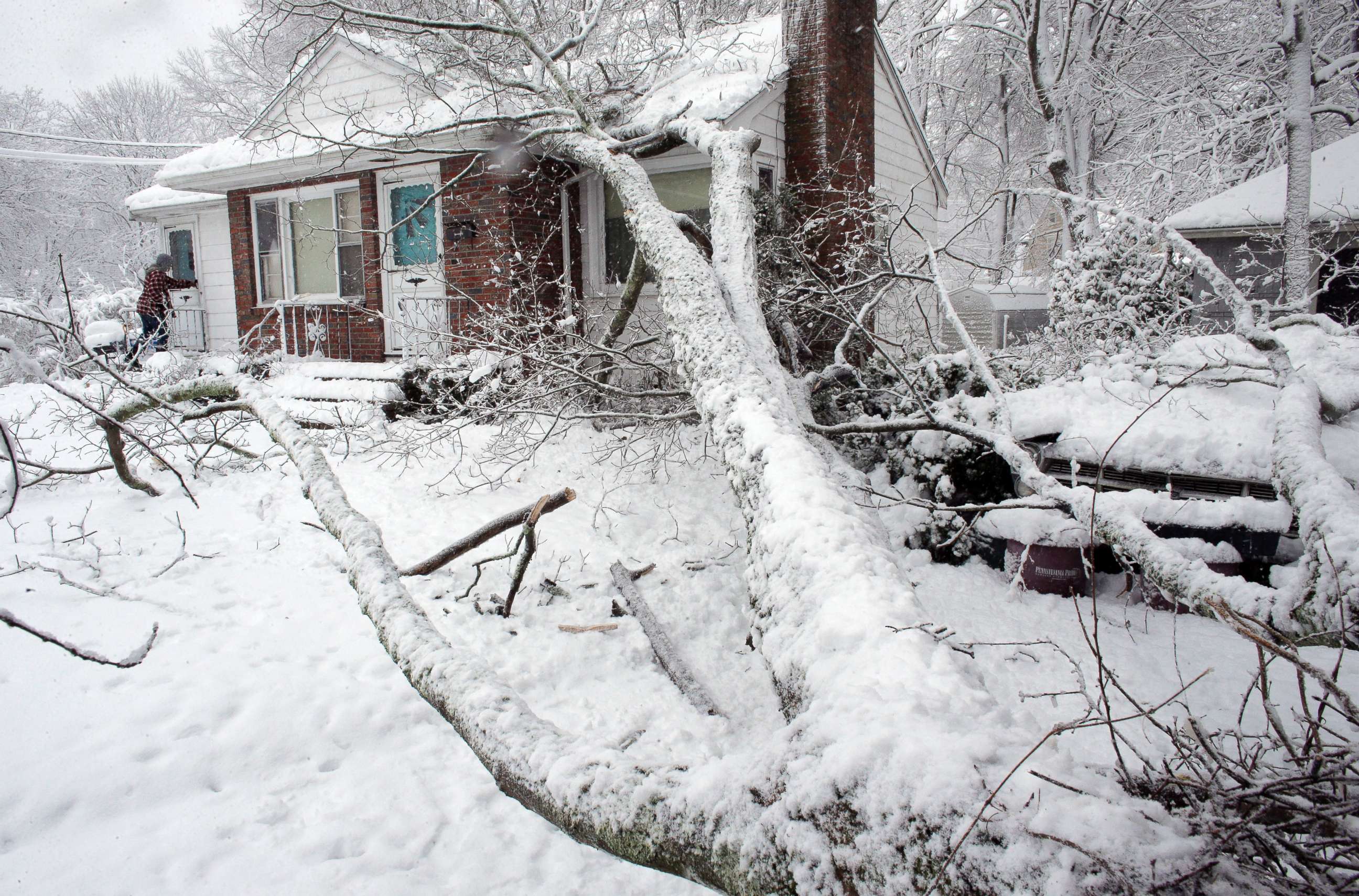 PHOTO: Brian Farrell, of Walpole, Mass., enters his home, March 8, 2018, after a tree fell on the house and a car, right, in Walpole, Mass. 