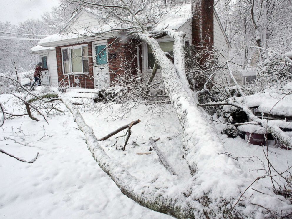PHOTO: Brian Farrell, of Walpole, Mass., enters his home, March 8, 2018, after a tree fell on the house and a car, right, in Walpole, Mass.