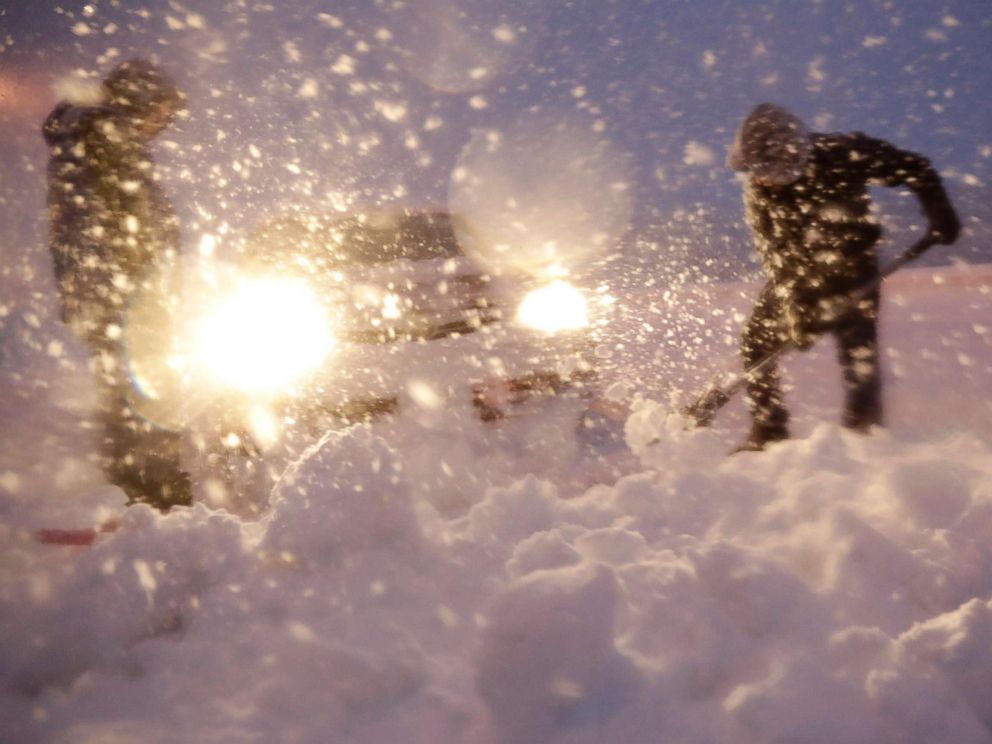 PHOTO: Men shovel snow while trying to free a vehicle stuck on a snowbank along Route 23 during a snowstorm, March 7, 2018, in Wayne, N.J.