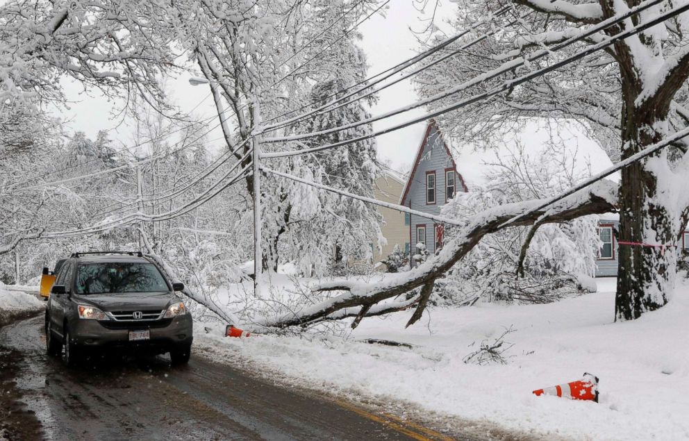 PHOTO: A motorist navigates around a downed limb partially blocking a road and resting on a power line after a snowstorm, March 8, 2018, in Northborough, Mass.  