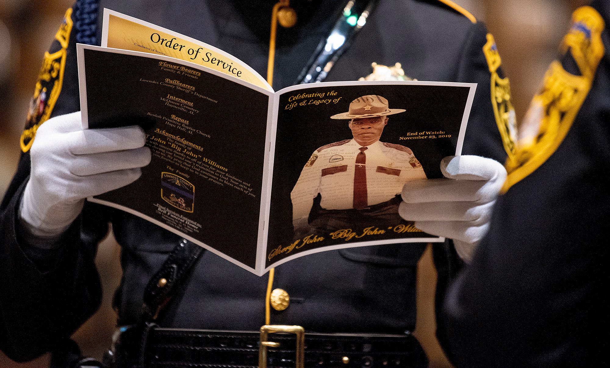 PHOTO: An attendee reads a program during the funeral of Lowndes County Sheriff "Big John" Williams at Garrett Coliseum in Montgomery, Ala., Dec. 2, 2019.