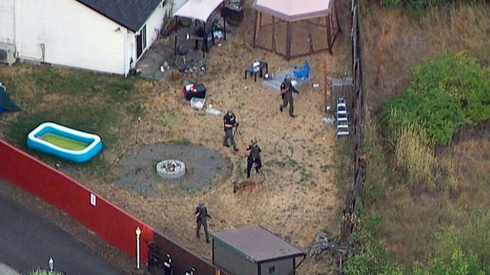 PHOTO: Law enforcement search the backyard of a home in pursuit of three suspects in the fatal shooting of a Clark County, Wash. Deputy Sheriff in Vancouver, B.C., Canada,  July 23, 2021 .