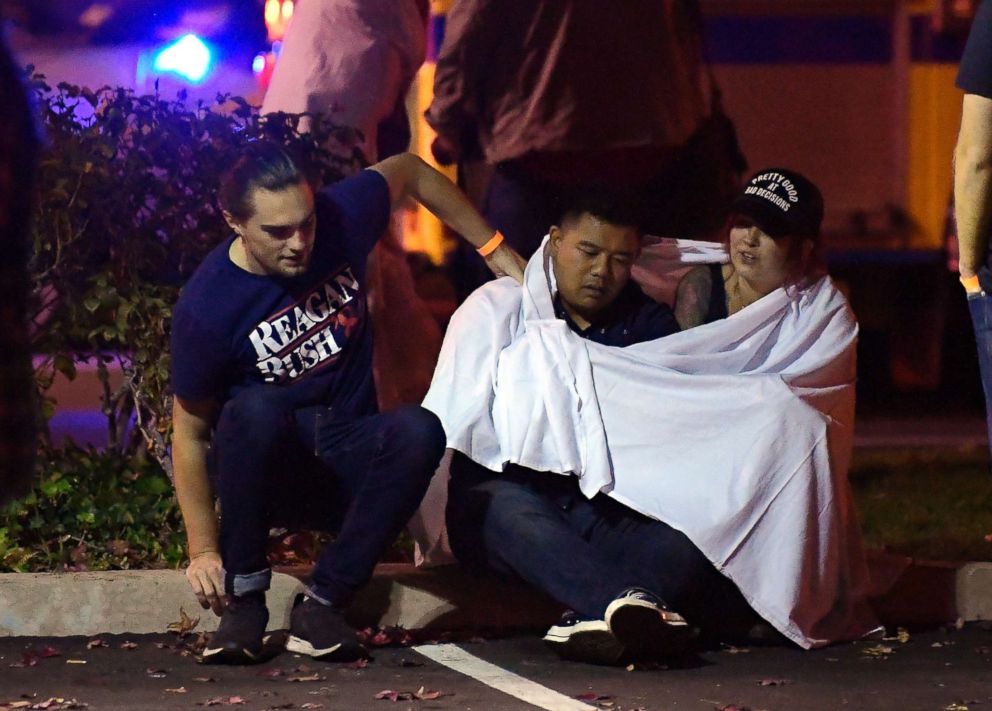 PHOTO: People comfort each other as they sit near the scene, Nov. 8, 2018, in Thousand Oaks, Calif., where a gunman opened fire Wednesday inside a country dance bar crowded with hundreds of people on "college night."