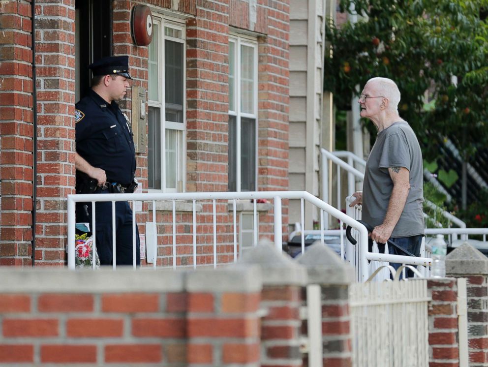 PHOTO: A police officer, left, talks with James Shields, Sr. in front a building where there was a shooting with multiple fatalities, including his son, in the Queens borough of New York, July 31, 2018.