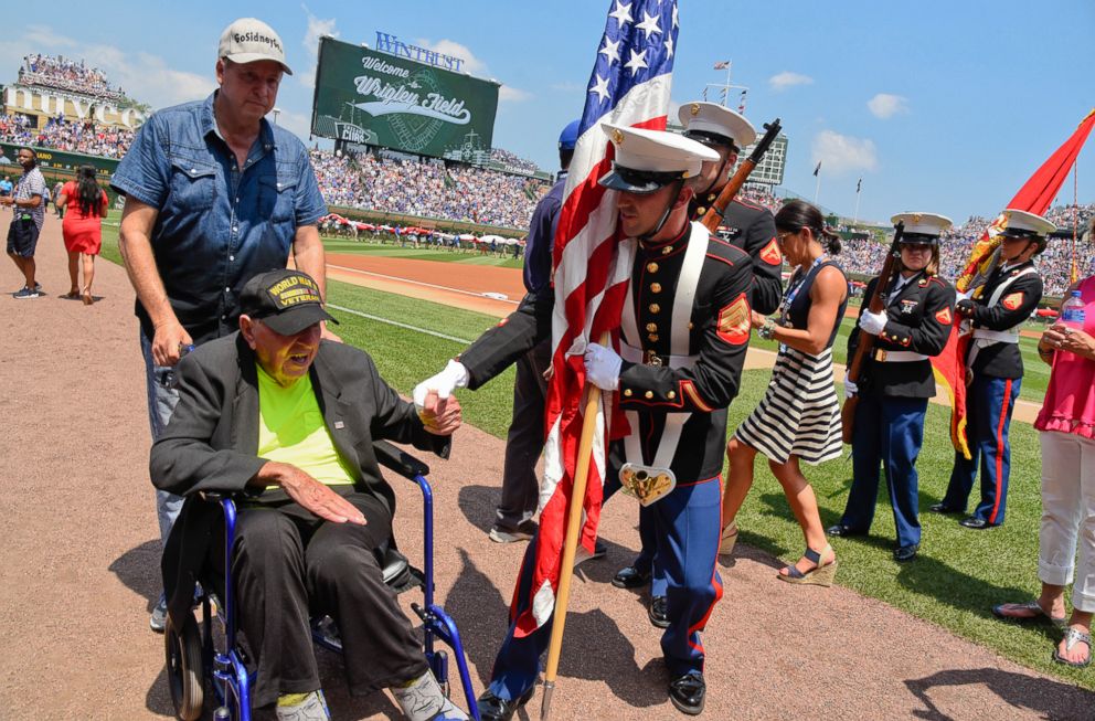 PHOTO: World War II veteran Sidney Walton, left, is greeted by a member of the color guard before a baseball game between the Chicago Cubs and Detroit Tigers, July 4, 2018, in Chicago.