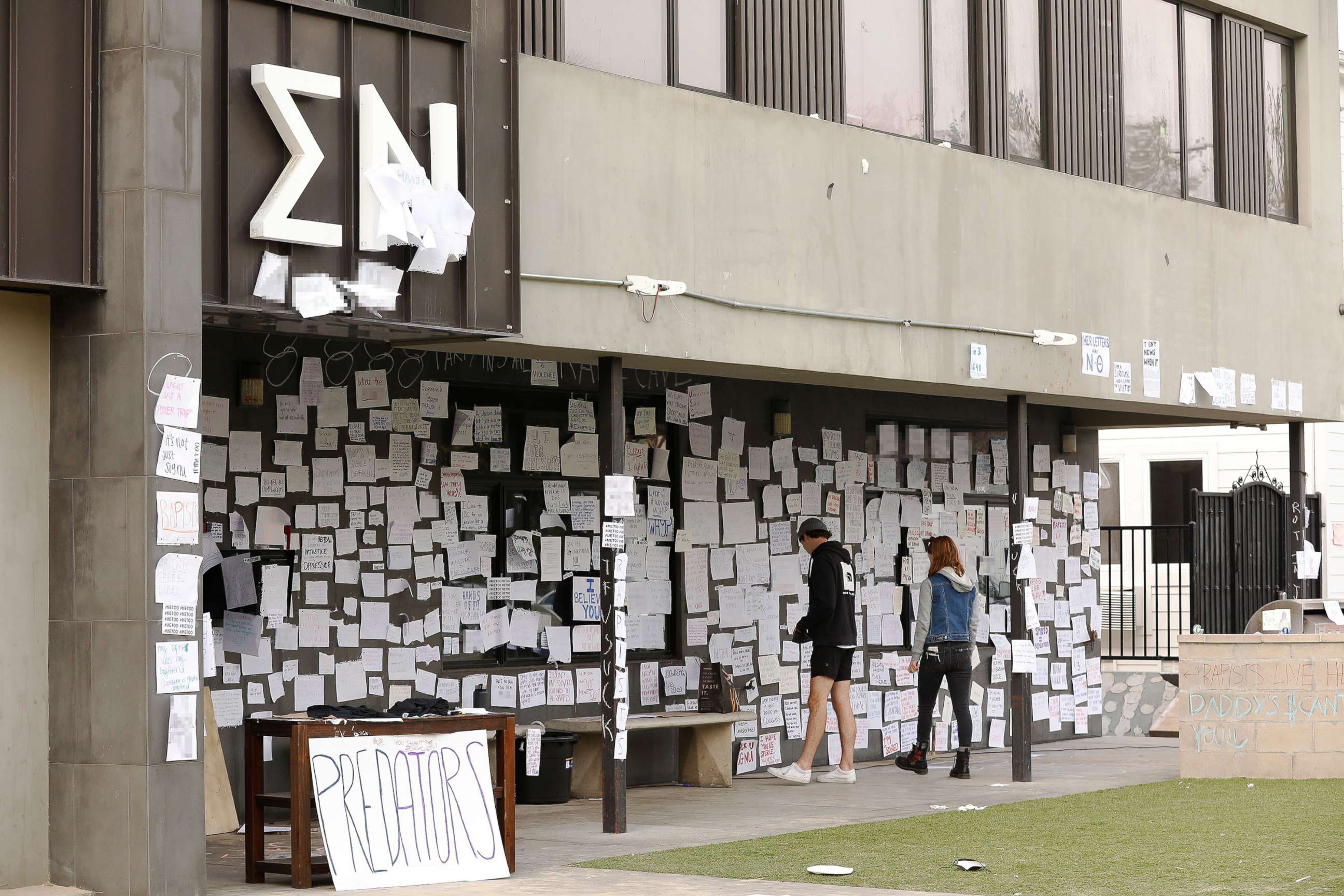 PHOTO: USC sophomore students Claire Smerdon and Charlie Littleworth re-tape notes attached to the Sigma Nu fraternity house near the USC campus, Oct. 22, 2021, in Los Angeles.
