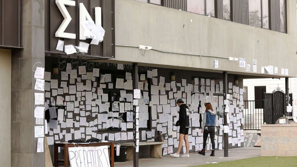 PHOTO: USC sophomore students Claire Smerdon and Charlie Littleworth re-tape notes attached to the Sigma Nu fraternity house near the USC campus, Oct. 22, 2021, in Los Angeles.