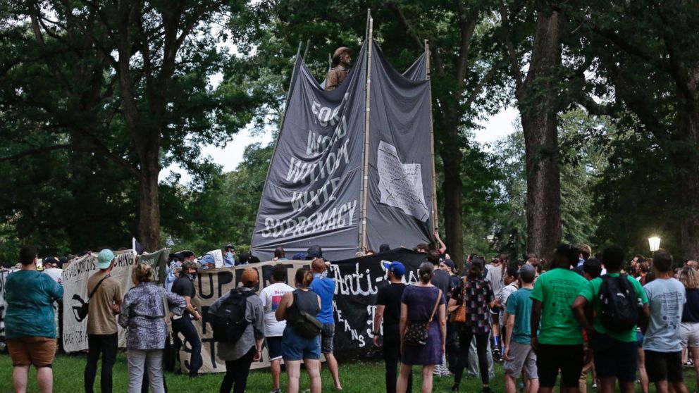 Banners are used to cover the statue known as Silent Sam as people gather during a rally to remove the confederate statue from campus at the University of North Carolina in Chapel Hill, N.C., Monday, Aug. 20, 2018.