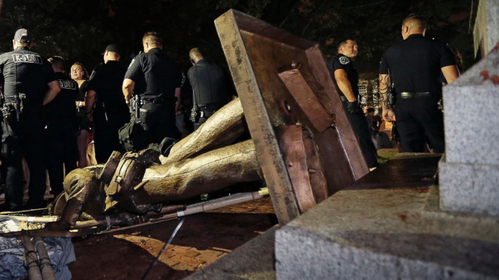 Police stand guard after the confederate statue known as Silent Sam was toppled by protesters on campus at the University of North Carolina in Chapel Hill, N.C., Monday, Aug. 20, 2018.