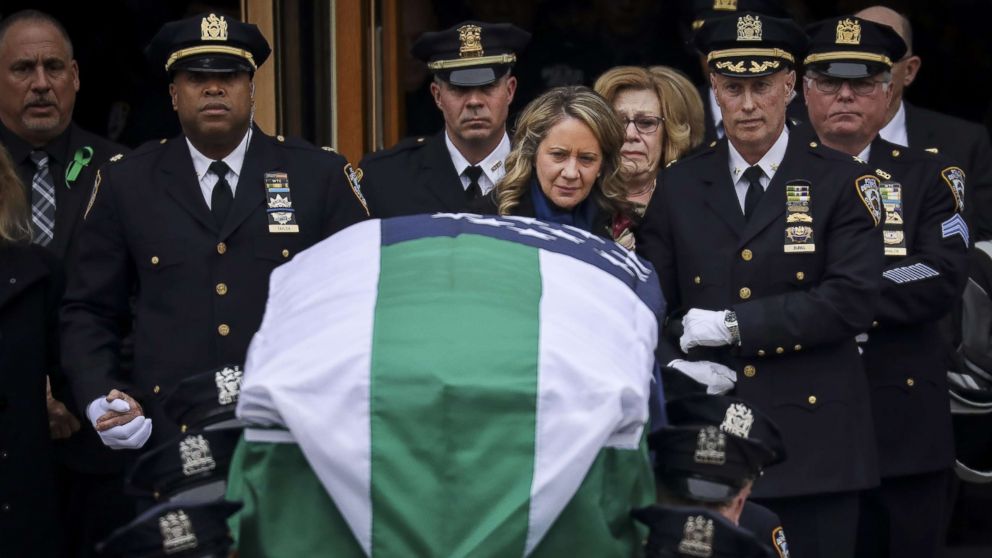 PHOTO: Leanne Simonsen, wife of fallen NYPD Detective Brian Simonsen, is escorted by officers as her late husband's remains are carried out of the church following his funeral service at the Church of St. Rosalie, Feb. 20, 2019 in Hampton Bays, N.Y.