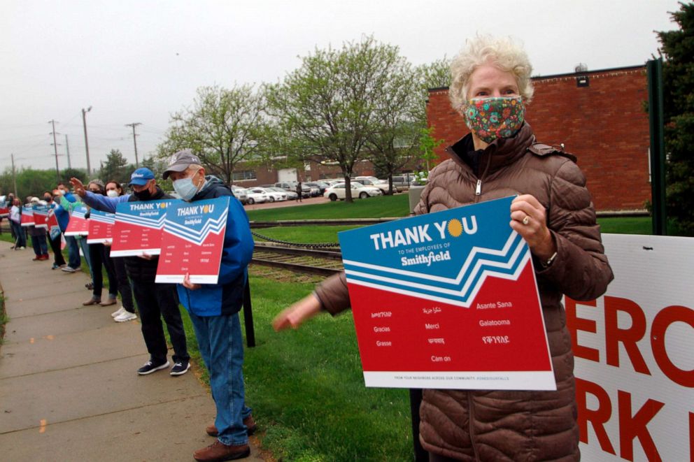 PHOTO: Sioux Falls resident Pat Lloyd, right, waves to greet employees of a Smithfield pork processing plant as they begin their shift on May 20, 2020, in Sioux Falls, S.D.