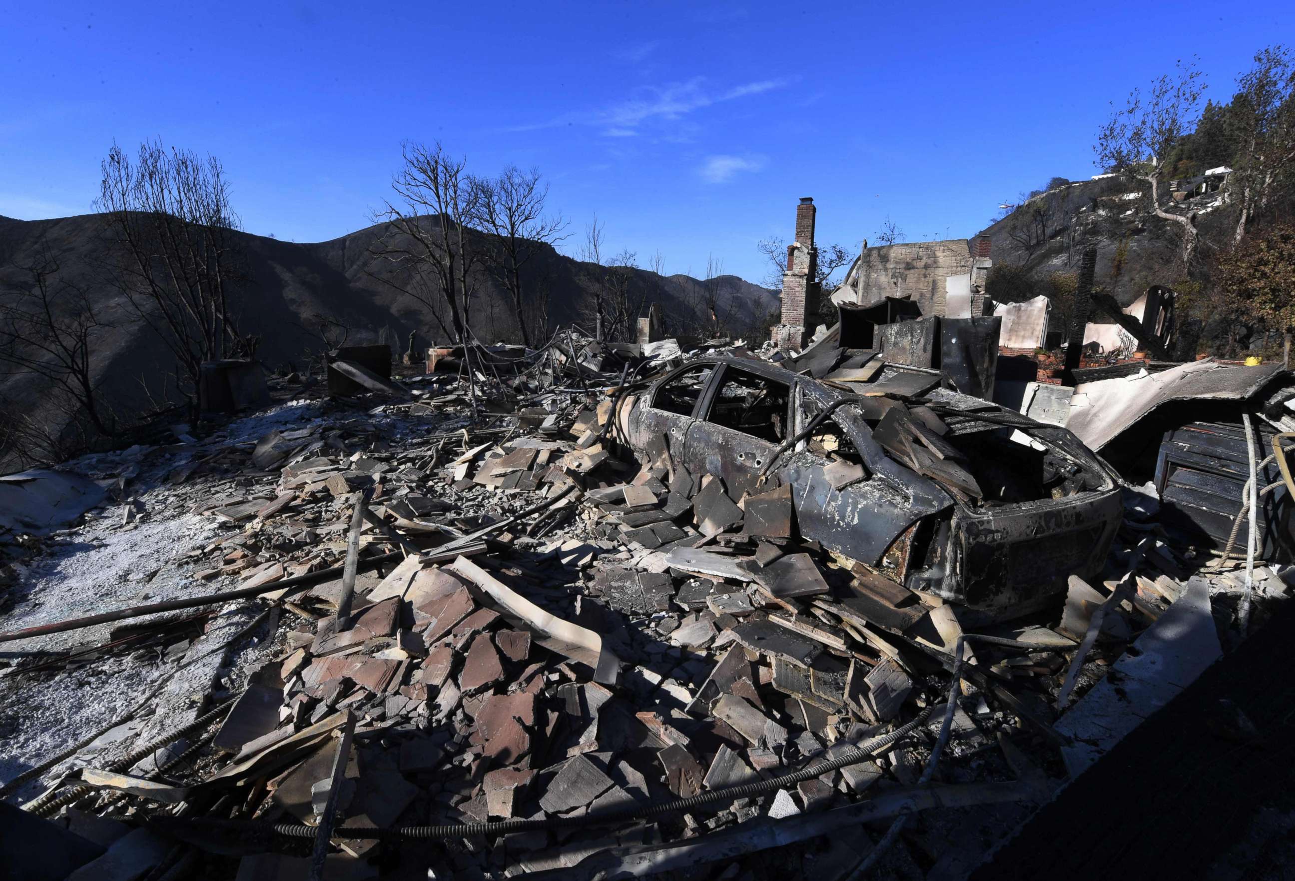 PHOTO: A burnt out house and car are seen after the Skirball wildfire swept through the exclusive enclave of Bel Air, Calif., Dec. 7, 2017.
