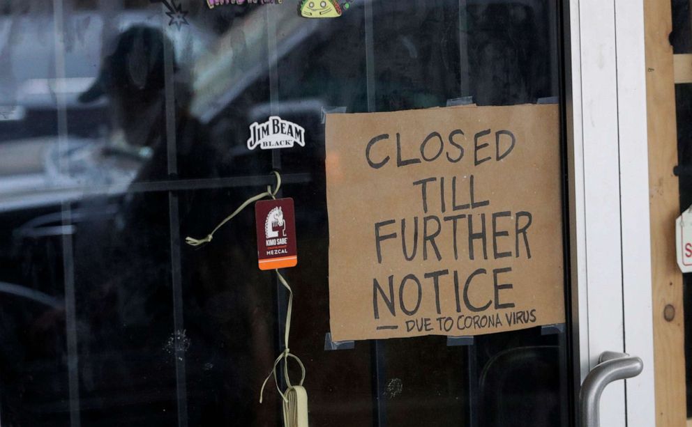 PHOTO: A man wearing a face mask is reflected in the door of a business closed due to the COVID-19 outbreak in San Antonio, Wednesday, April 22, 2020. 