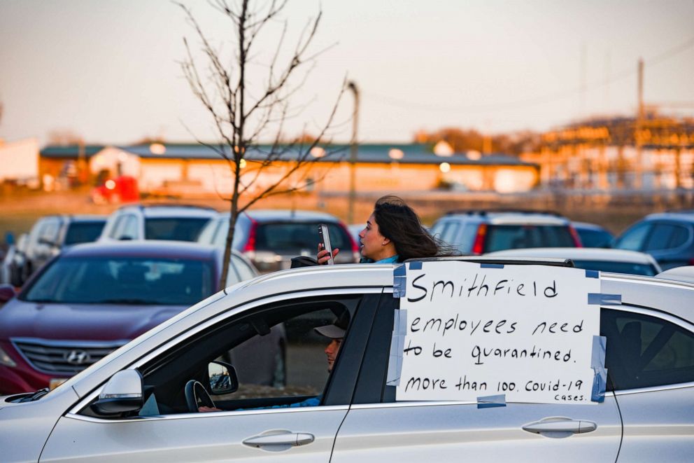 PHOTO: A protester records the demonstration on her phone out the sunroof of her car while driving in solidarity with Smithfield Food, Inc. employees, April 9, in Sioux Falls, S.D.