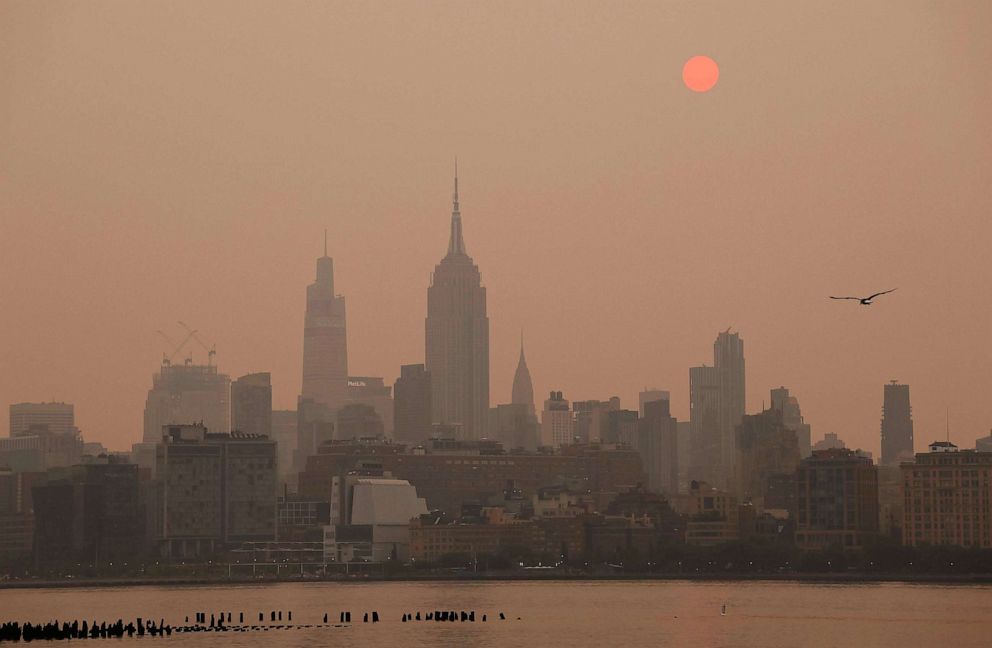 PHOTO: The sun is shrouded as it rises in a hazy, smokey sky behind the Empire State Building in New York City, June 6, 2023.