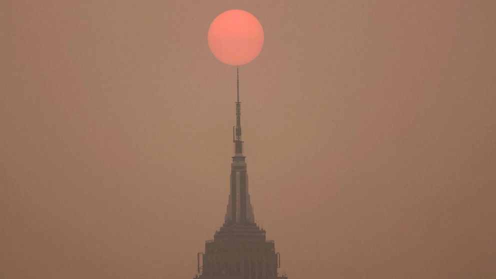 PHOTO: The sun is shrouded as it rises in a hazy, smokey sky behind the Empire State Building in New York City, June 6, 2023.
