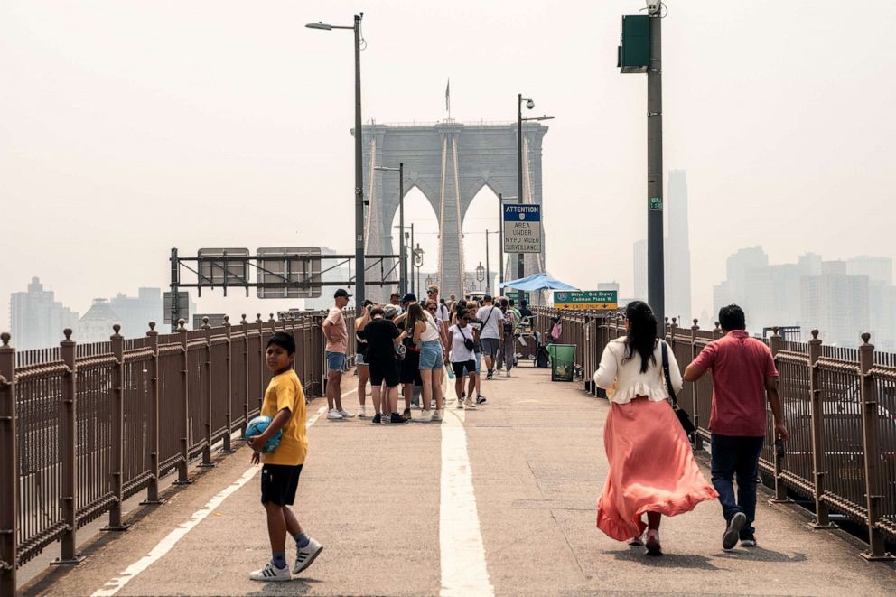 PHOTO: People walk over the Brooklyn Bridge as smoke from wildfires in Canada shrouds the area on June 30, 2023 in New York City.