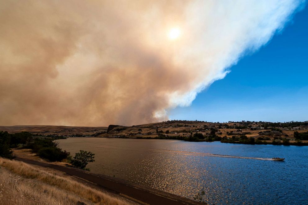 PHOTO: A boat heads down the Snake River as smoke from the Asotin Complex Fire west of Clarkston, Wash., wafts eastward into Lewiston, Idaho, on July 7, 2021.