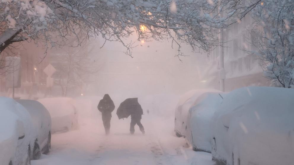 PHOTO: People walk down a snow-covered street at daybreak in Hoboken, NJ, Feb. 23, 2026.