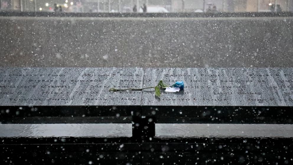 A memorial flower is left by a name at the 9/11 Memorial during a wet snowfall, Thursday Nov. 15, 2018, in New York.