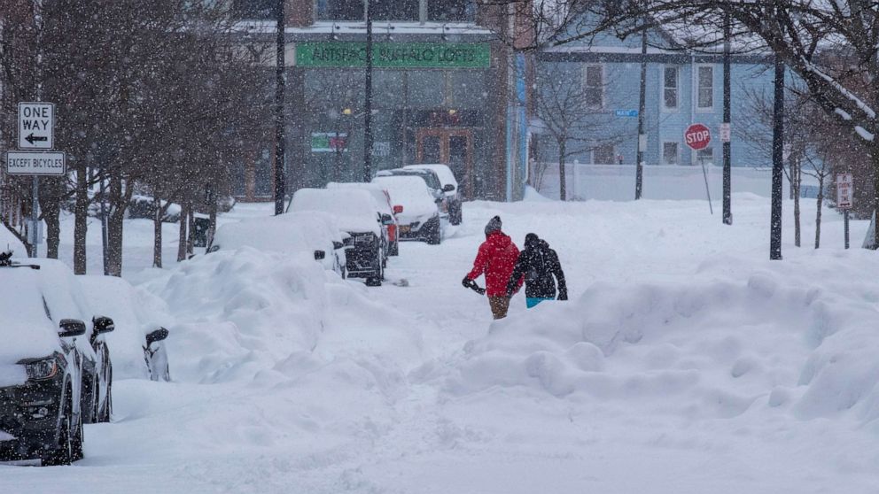 PHOTO: People move about the streets of the Elmwood Village neighborhood of Buffalo, N.Y., Monday, Dec. 26, 2022, after a massive snow storm blanketed the city. Along with drifts and travel bans, many streets were impassible due to abandoned vehicles.