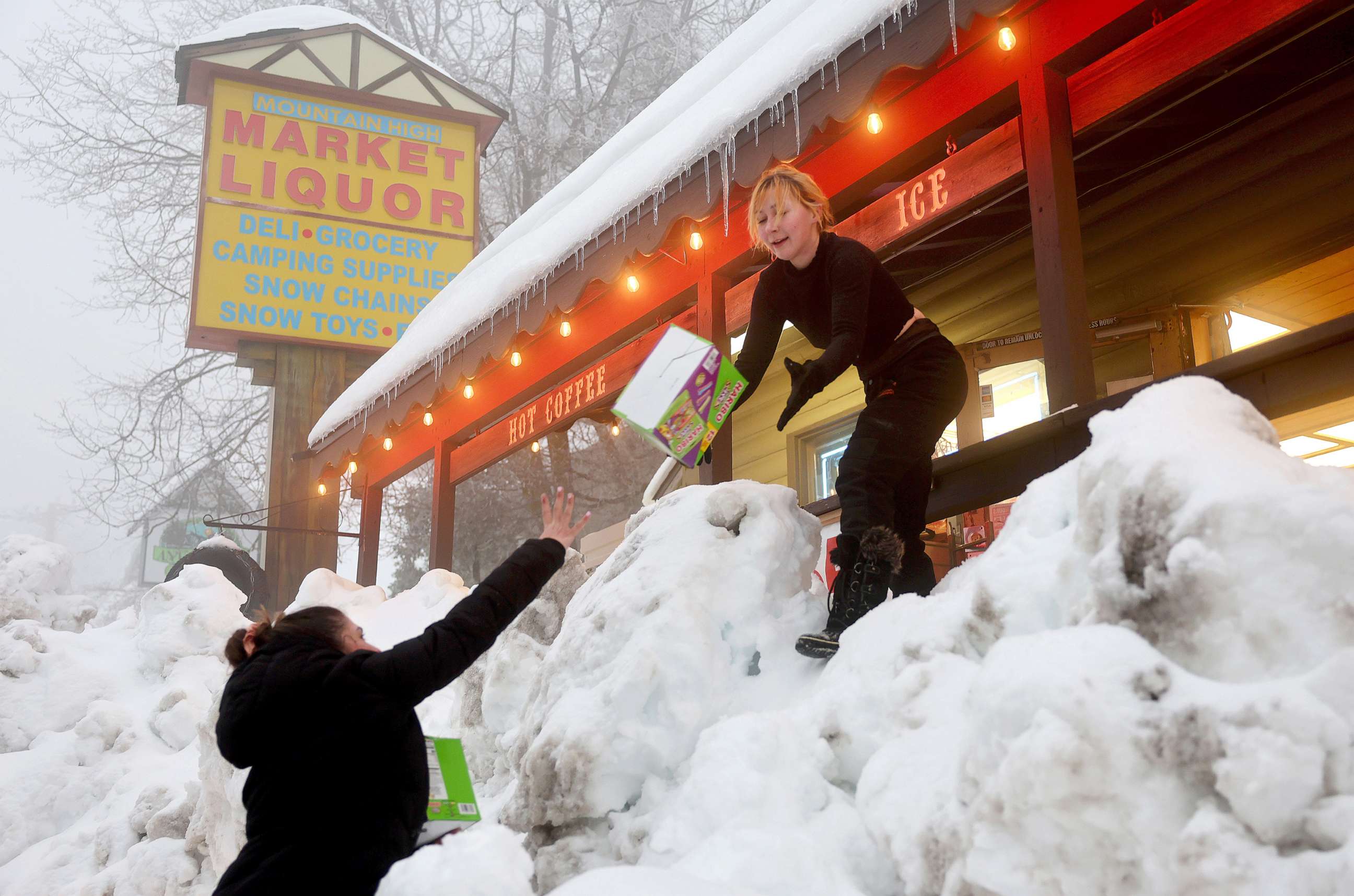 PHOTO: Resident Jessica Neakarse (R) helps Annie Ibrahim (L) re-stock Mountain High Market after a series of winter storms dropped more than 100 inches of snow in the San Bernardino Mountains in Southern California, on March 6, 2023, in Twin Peaks, Calif.