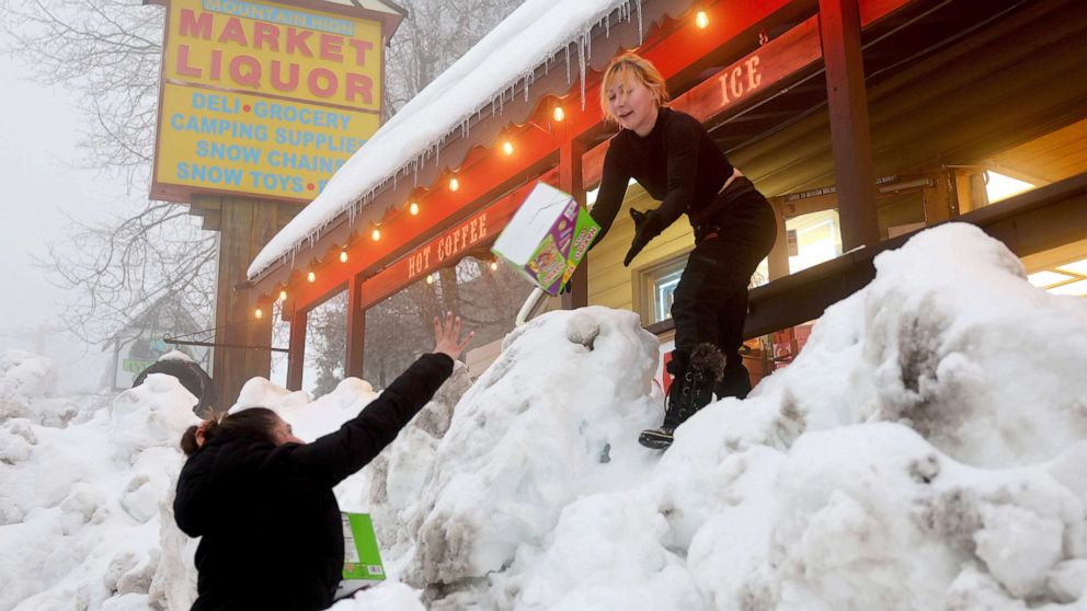 PHOTO: Resident Jessica Neakarse (R) helps Annie Ibrahim (L) re-stock Mountain High Market after a series of winter storms dropped more than 100 inches of snow in the San Bernardino Mountains in Southern California, on March 6, 2023, in Twin Peaks, Calif.