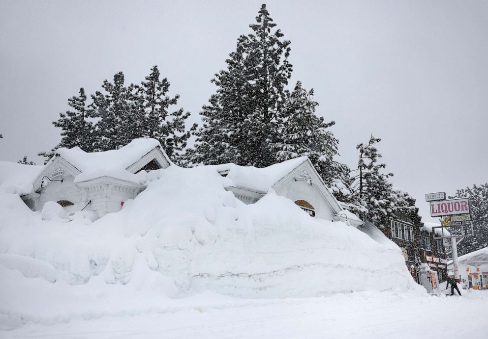 PHOTO: Brian Dunham shovels snow near snowbanks piled up from previous storms during another winter storm in the Sierra Nevada mountains on March 10, 2023, in Mammoth Lakes, Calif.