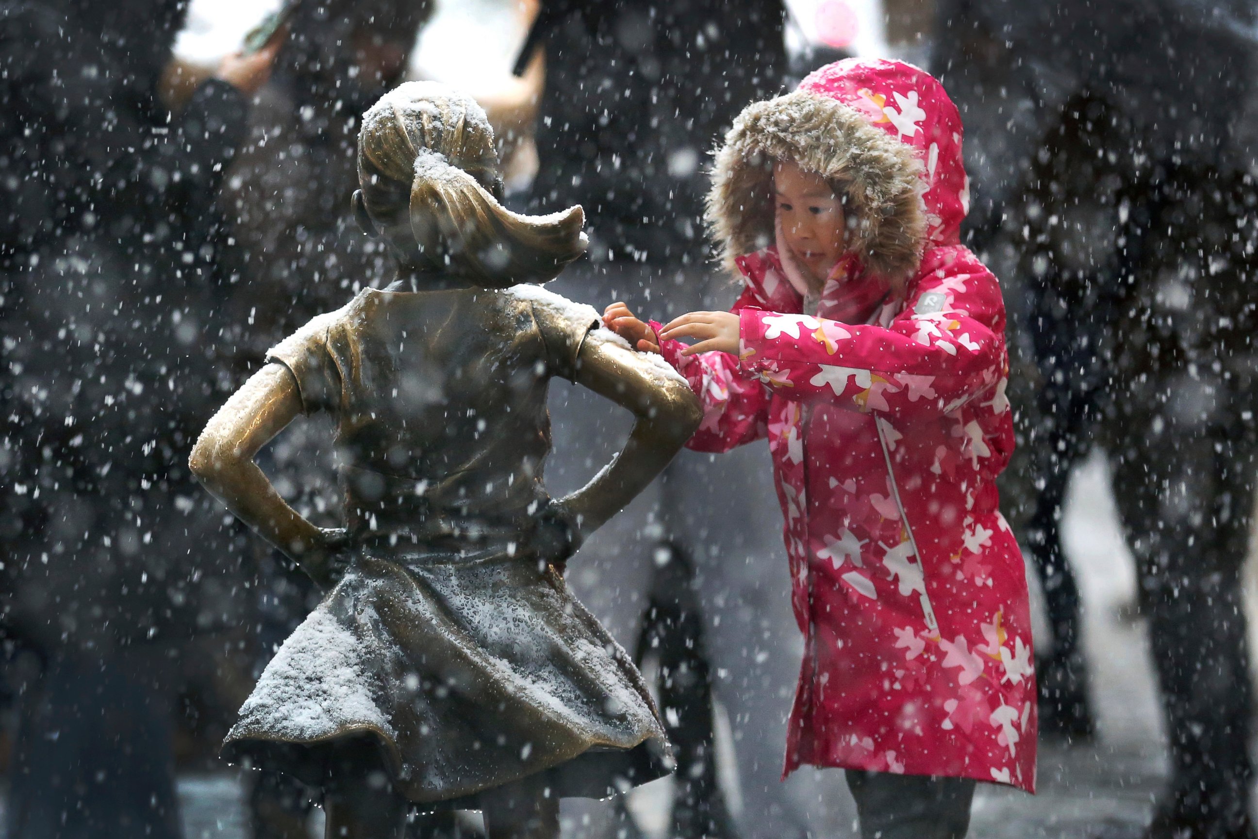 PHOTO: A young girl brushes off snow on the Fearless Girl statue in lower Manhattan on Thursday, Nov. 15, 2018, in New York. One of the first big storms of the season moved across the eastern half of the country on Thursday. 