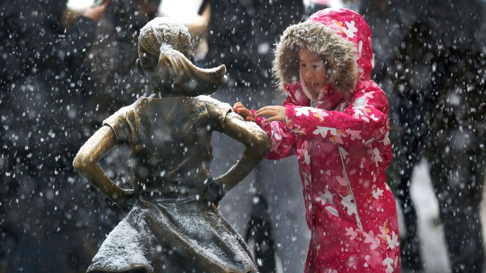 PHOTO: A young girl brushes off snow on the Fearless Girl statue in lower Manhattan on Thursday, Nov. 15, 2018, in New York. One of the first big storms of the season moved across the eastern half of the country on Thursday. 