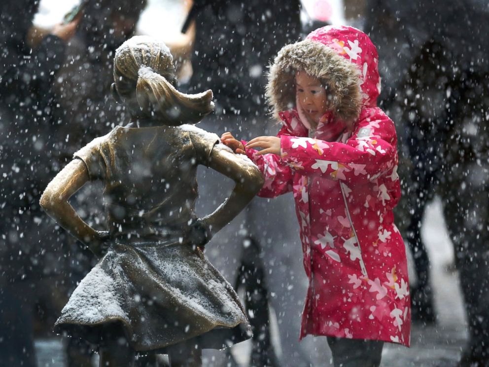 PHOTO: A young girl brushes off snow on the Fearless Girl statue in lower Manhattan on Thursday, Nov. 15, 2018, in New York. One of the first big storms of the season moved across the eastern half of the country on Thursday. 