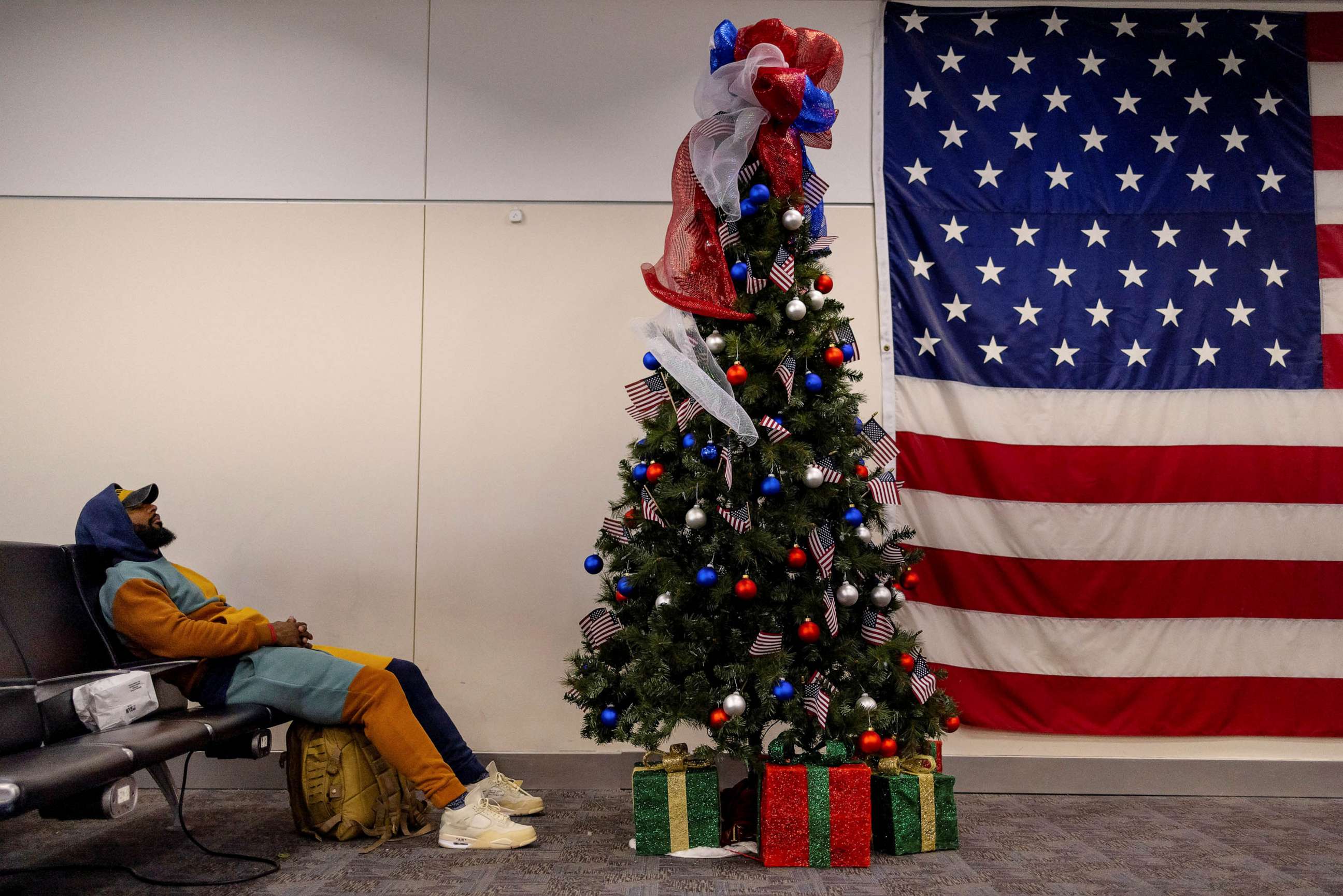 PHOTO: A man sleeps next to a Christmas tree at the Atlanta international airport in Atlanta, Georgia, Dec. 7, 2022.