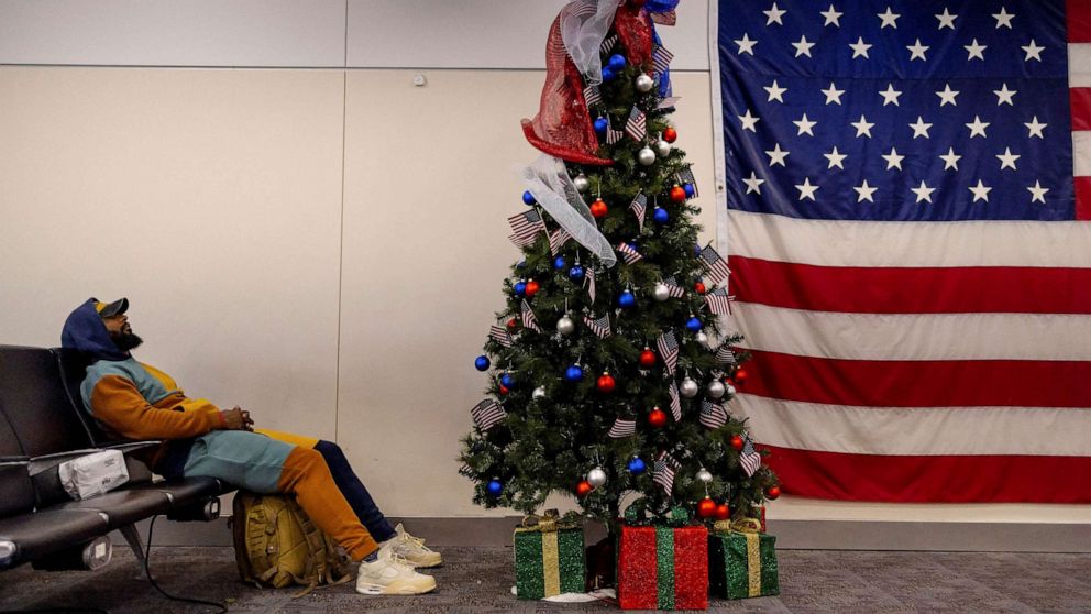 PHOTO: A man sleeps next to a Christmas tree at the Atlanta international airport in Atlanta, Georgia, Dec. 7, 2022.