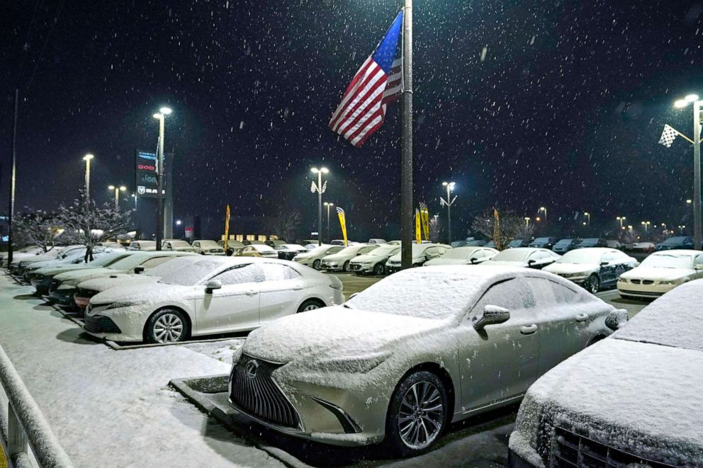 PHOTO: An American flag snaps in the wind while snow and ice cover new automobiles at a dealership on Jan. 10, 2021, in Jackson, Miss. A winter storm is coating parts of Texas, Louisiana and Mississippi with snow on Sunday and into Monday morning.