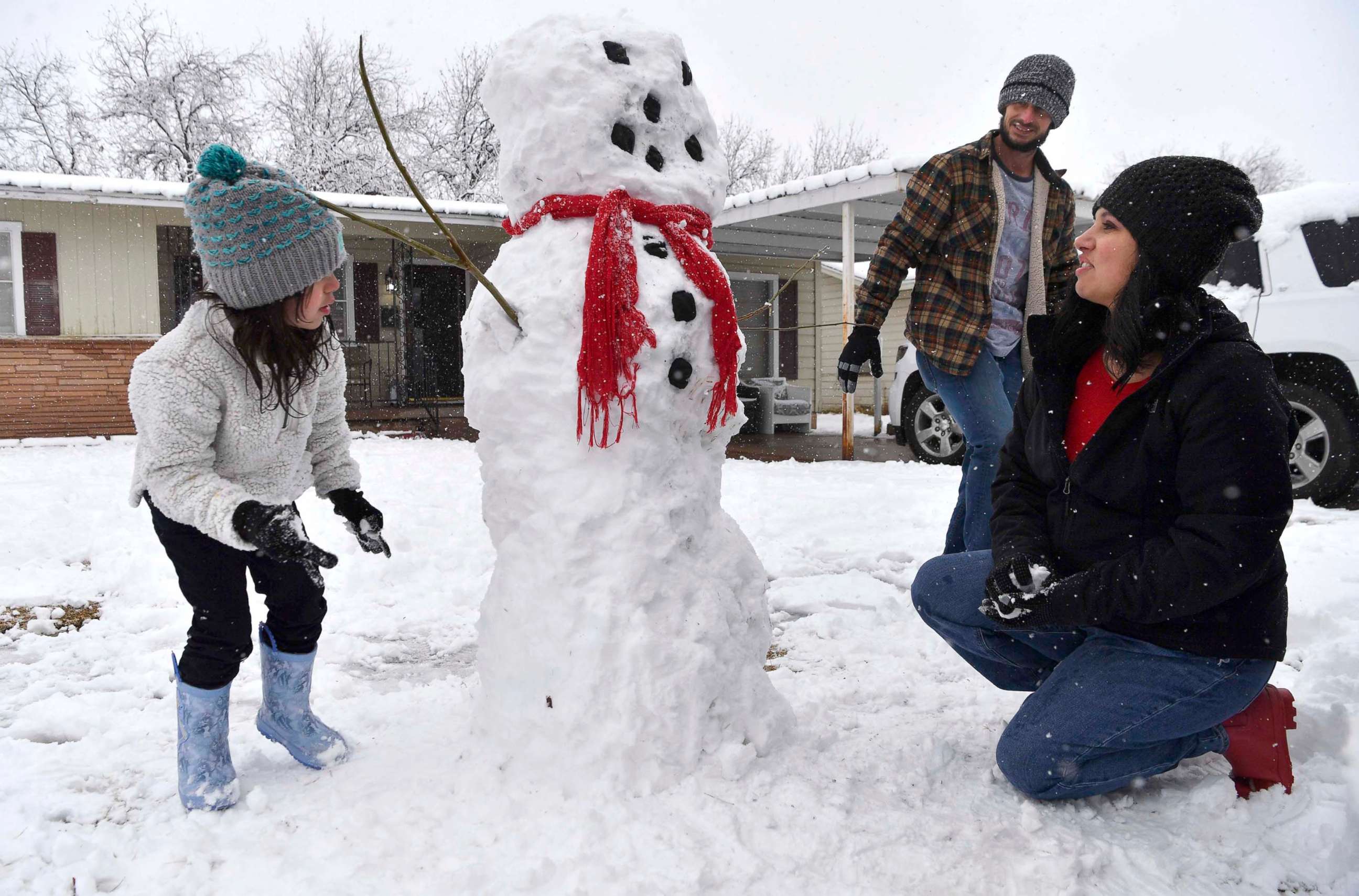 PHOTO: Taylor Young, 5, inspects her handiwork as she builds a snowman with her parents Paul and Brittney during Sunday's morning snowfall in Abilene, Texas Jan. 10, 2021.