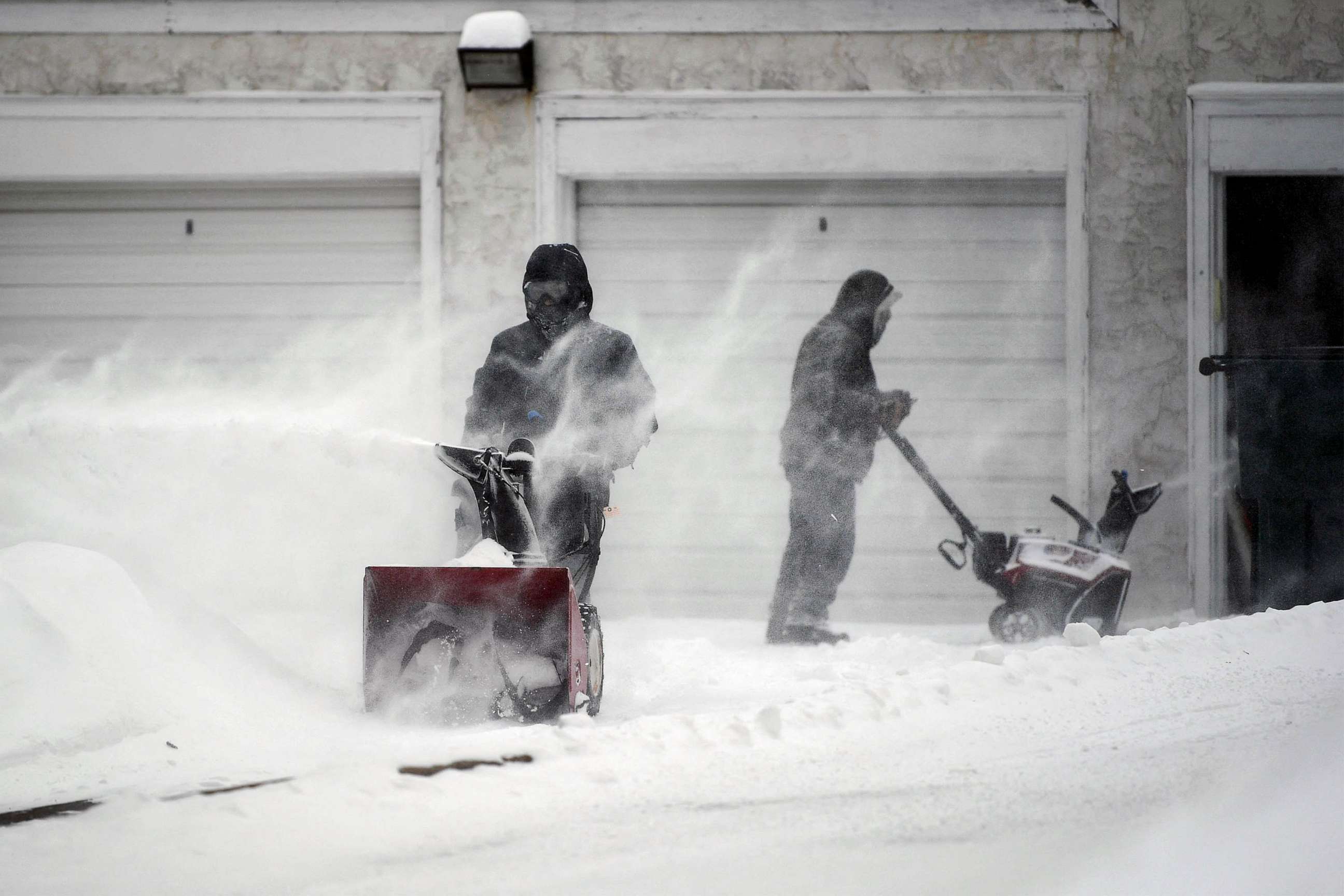 PHOTO: People clear snow from a driveway during a snowstorm in Minneapolis, Feb. 22, 2023.