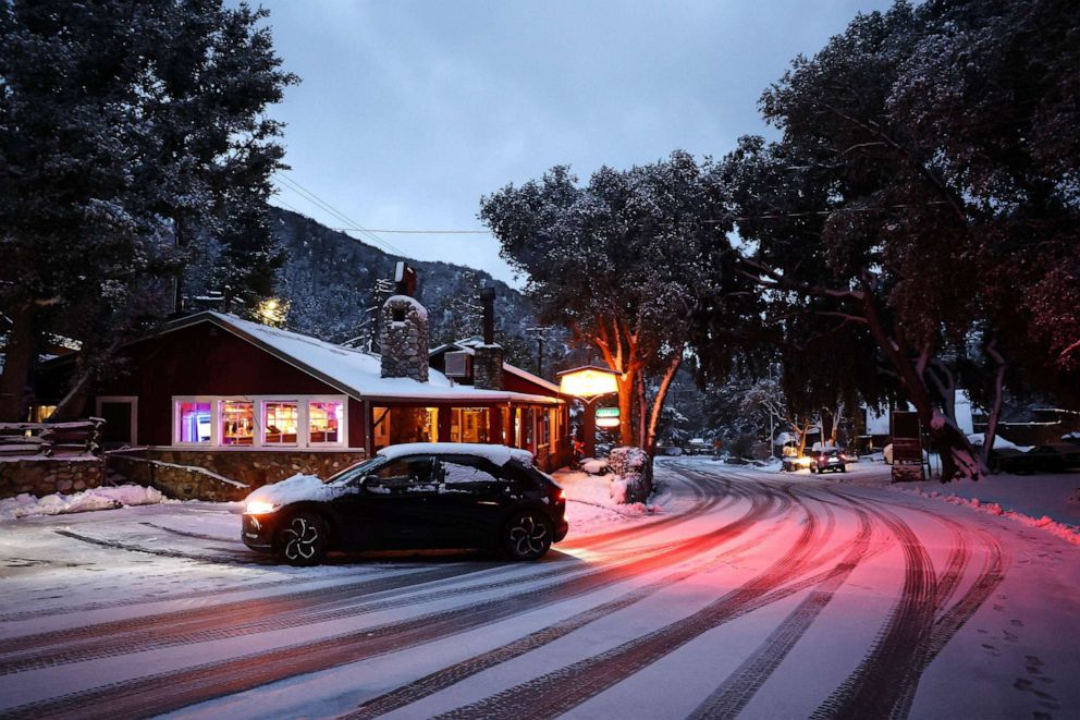 PHOTO: A car backs out next to a restaurant as snow blankets the town in the San Gabriel Mountains, in San Bernardino County along the border of Los Angeles County, Feb. 23, 2023 in Mount Baldy, Calif.