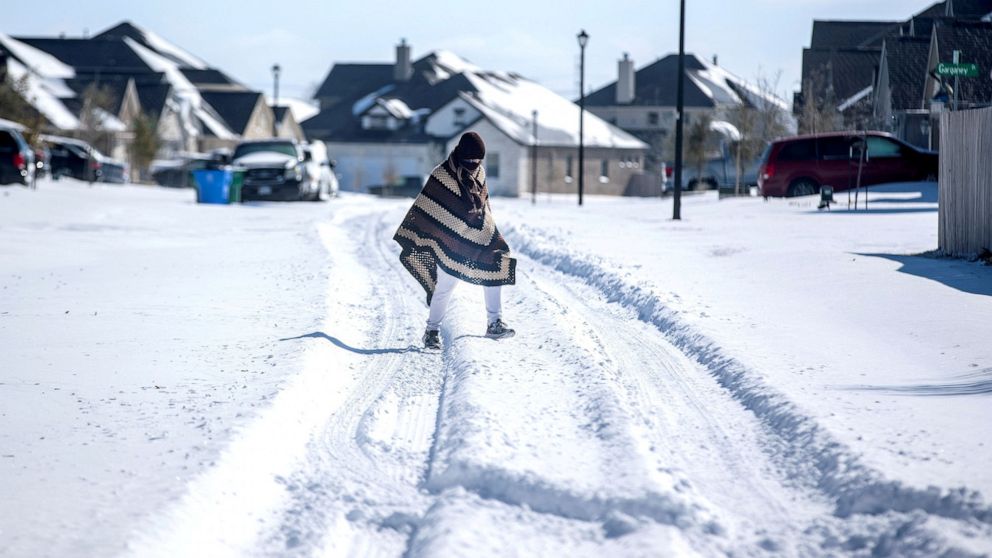 PHOTO: A man walks to his friend's home in a neighborhood without electricity as snow covers the BlackHawk neighborhood in Pflugerville, Texas, Feb. 15, 2021.