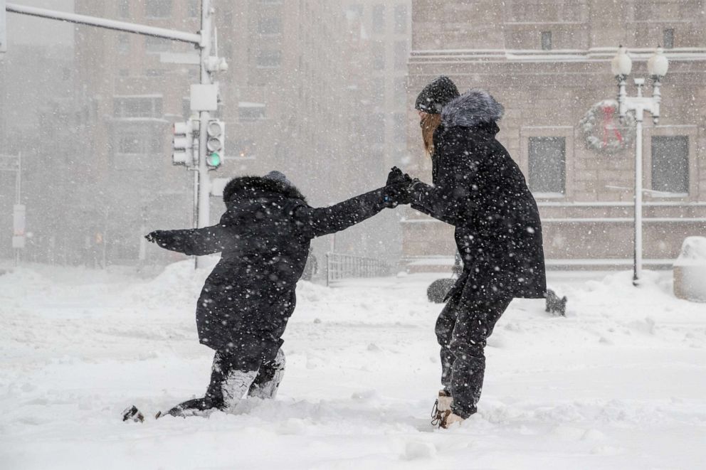 PHOTO: A woman helps her friend stand up after slipping on the sidewalk on Dec. 17, 2020 in Boston.