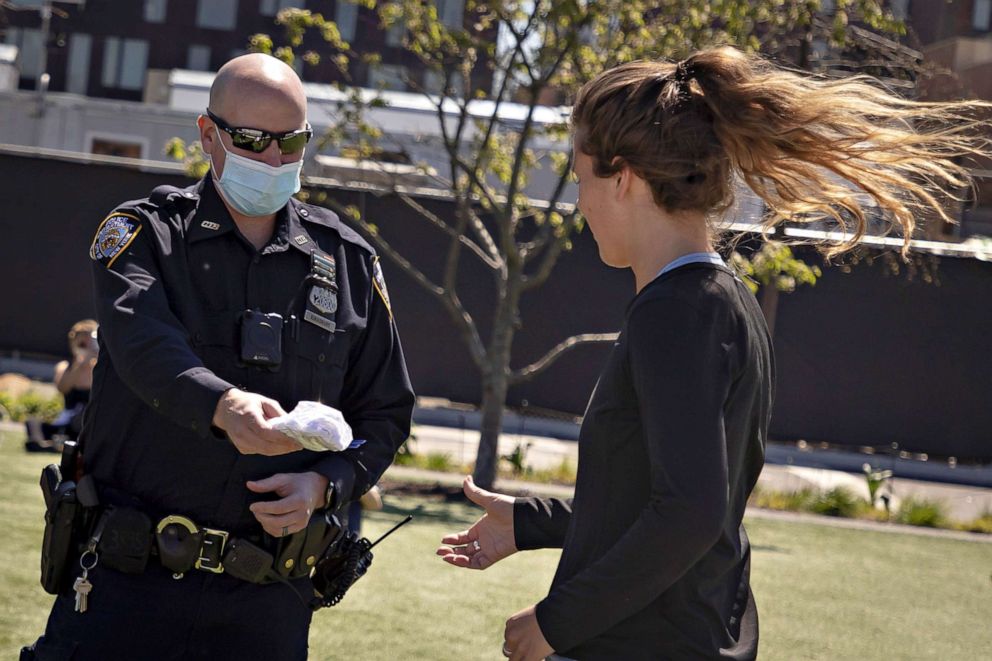 PHOTO: A police officer distributes face masks in Domino Park in the Brooklyn borough of New York City, May 2, 2020.