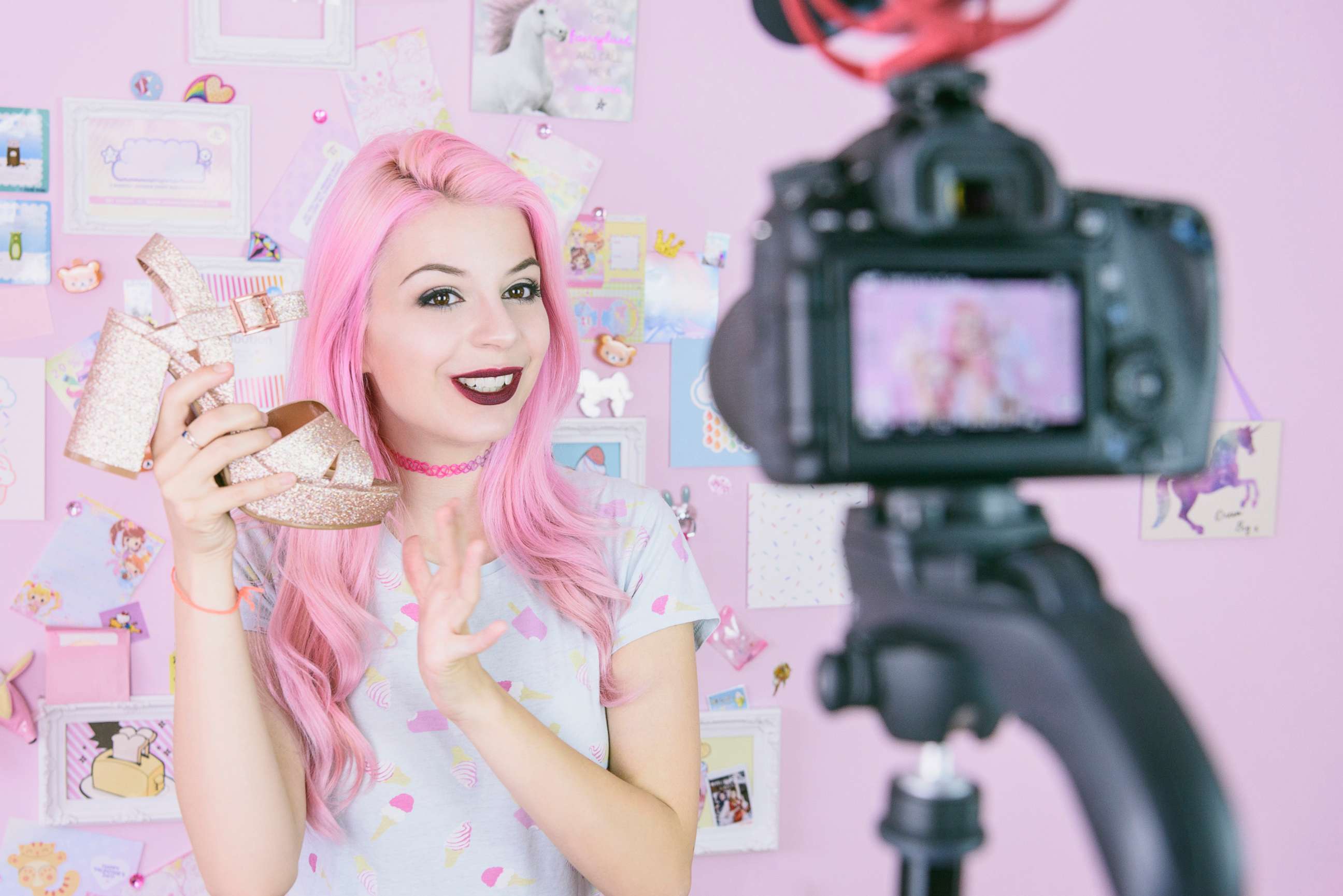 PHOTO: A staged photo of someone portraying a Social media influencer reviewing footwear, she is vlogging about women's fashion and filming herself at home on a video camera.