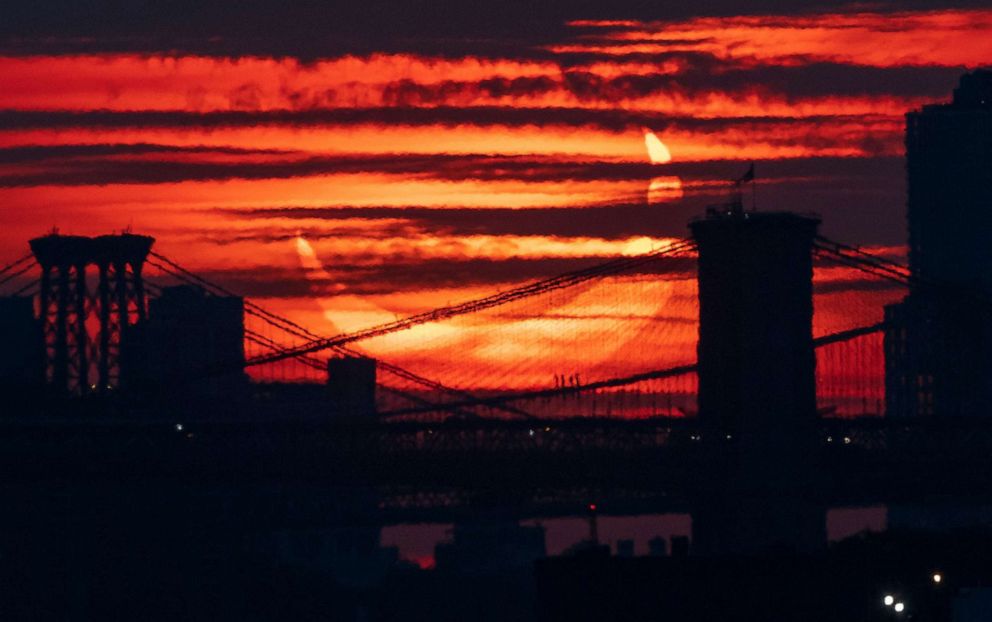 PHOTO: A partial solar eclipse rises over bridges crossing the East River in New York, June 10, 2021.