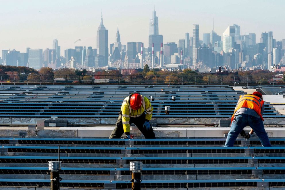 PHOTO: Framed by the Manhattan skyline electricians install solar panels on top of the Terminal B garage at LaGuardia Airport, Nov. 9, 2021, in the Queens borough of New York.