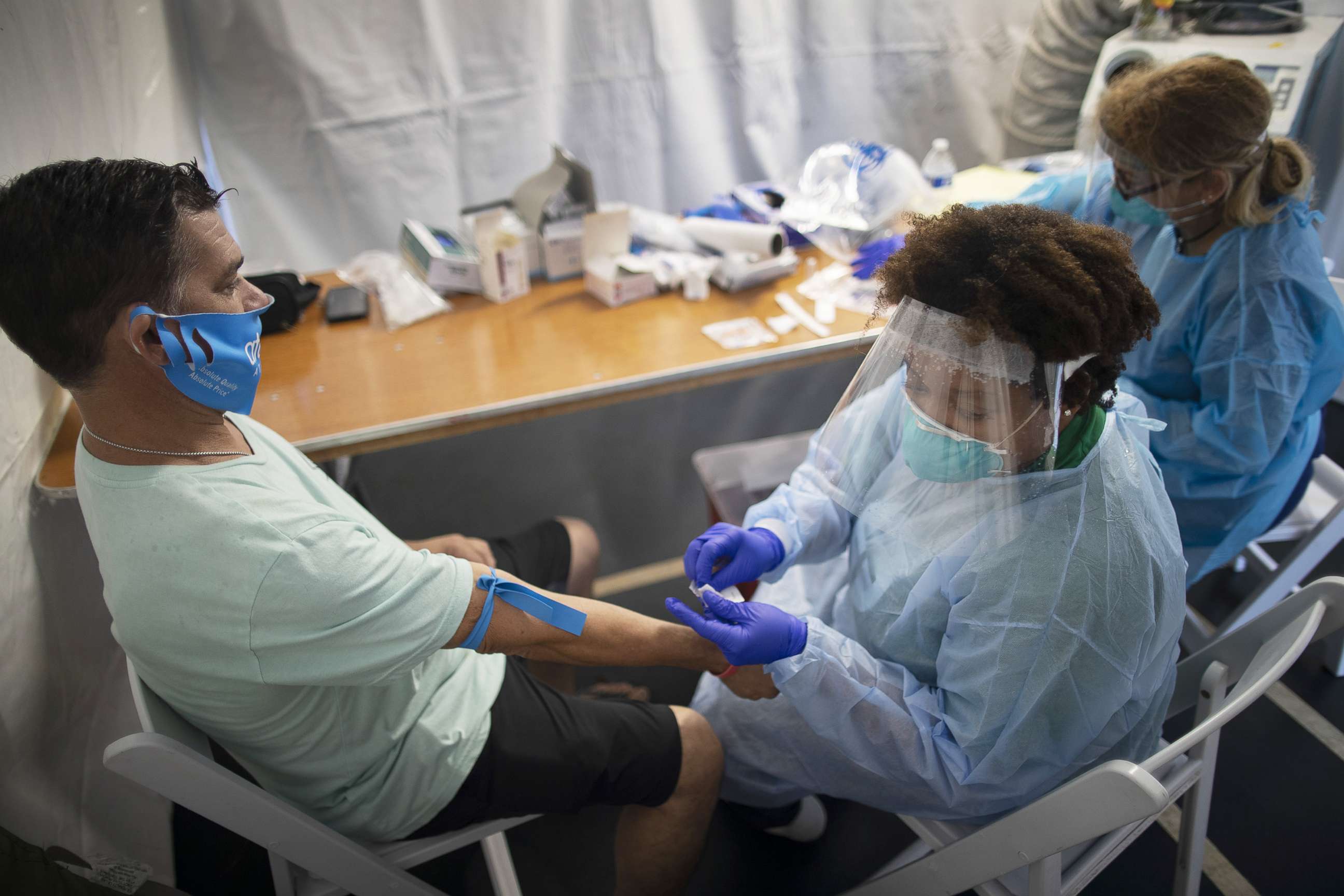 PHOTO: Dr. Jacqueline Delmont, Chief Medical Officer of SOMOS Community Care, prepares to take blood from Eddie Mena to test for COVID-19 antibodies in a medical tent, July 22, 2020, in Miami Lakes, Fla. 