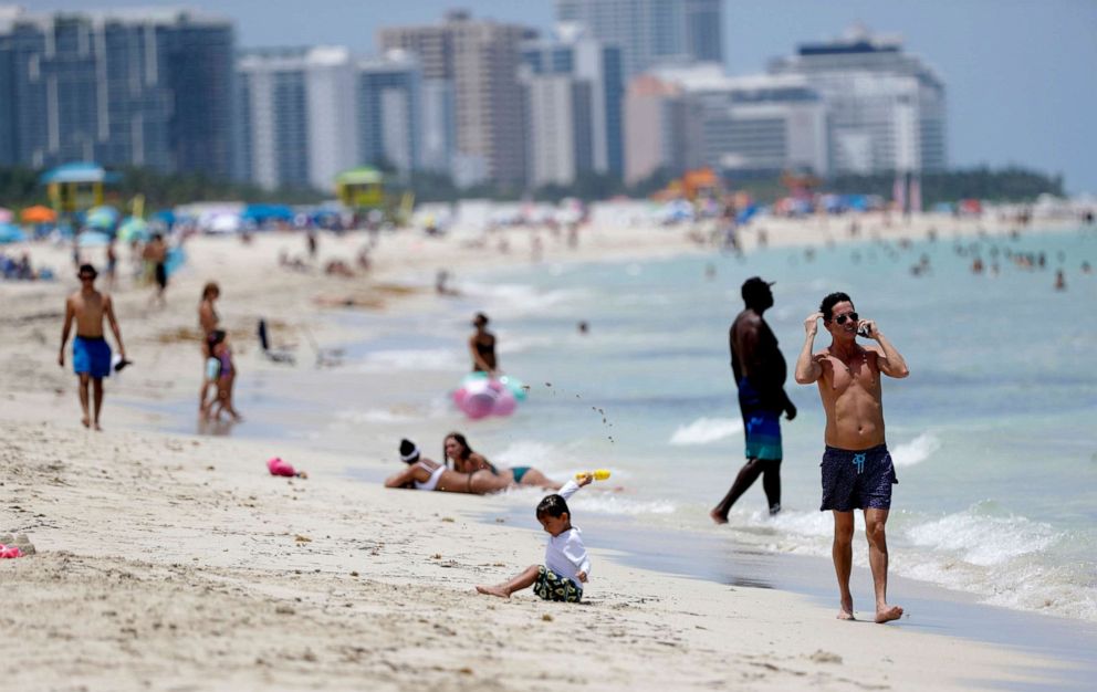 PHOTO: Beach goers walk along the shore on Miami Beach, Florida's famed South Beach, July 7, 2020. Beaches in Miami-Dade County reopened Tuesday after being closed July 3 through 6 to prevent the spread of coronavirus.